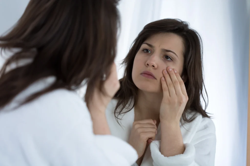 une femme qui regarde des cernes marquées dans le mirroir
