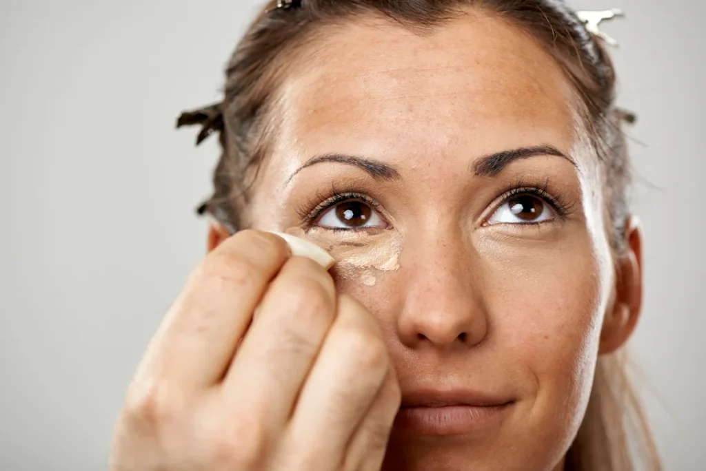 Une femme qui se maquille pour cacher des cernes