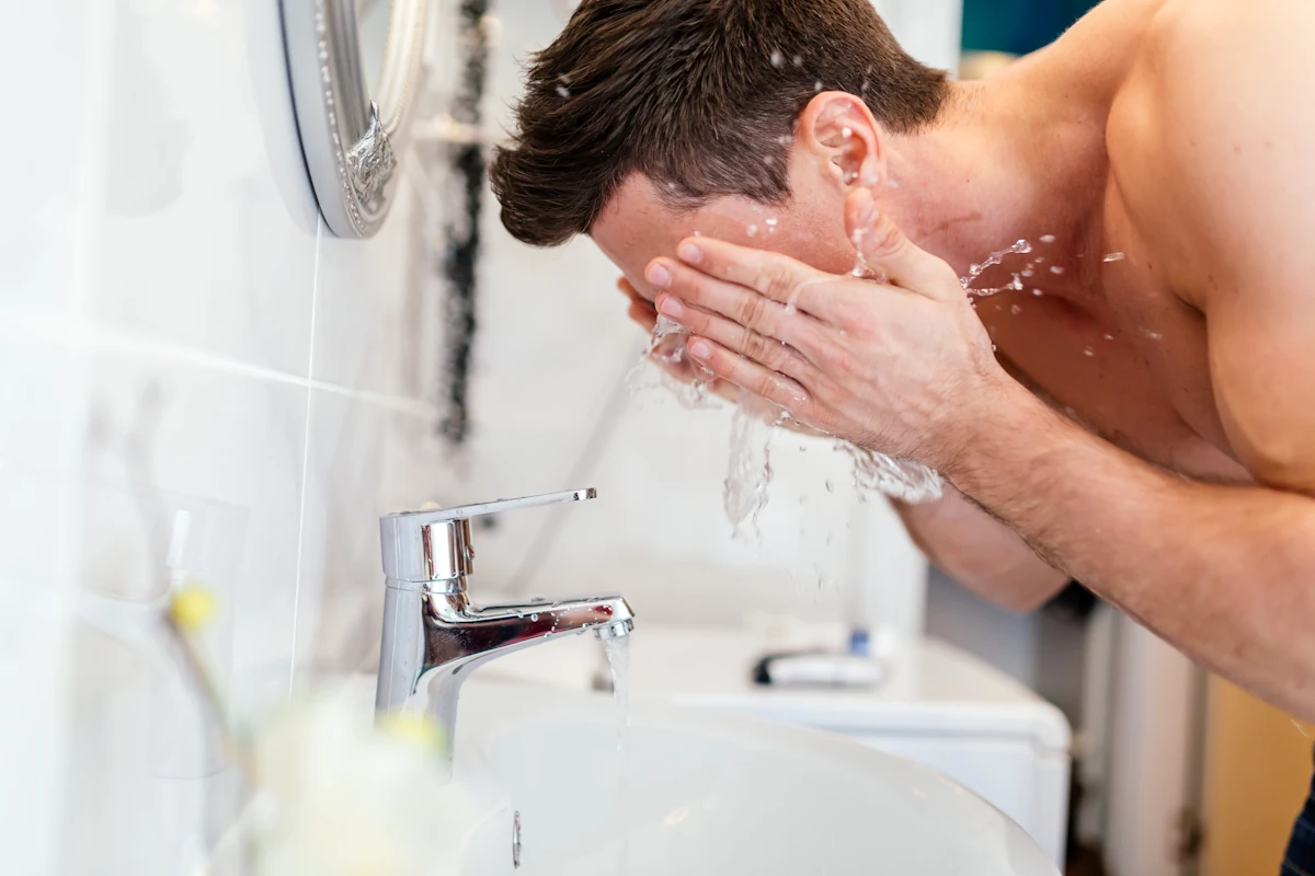 Un homme qui se nettoie votre visage à l'eau tiède avant de se raser la barbe