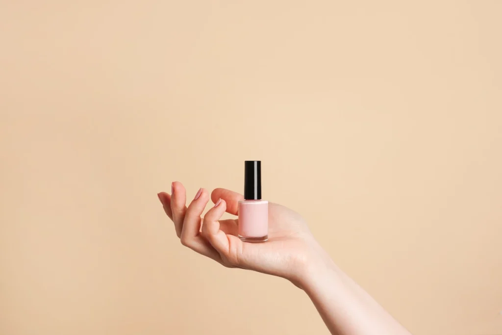 Une main qui tient un vernis nude